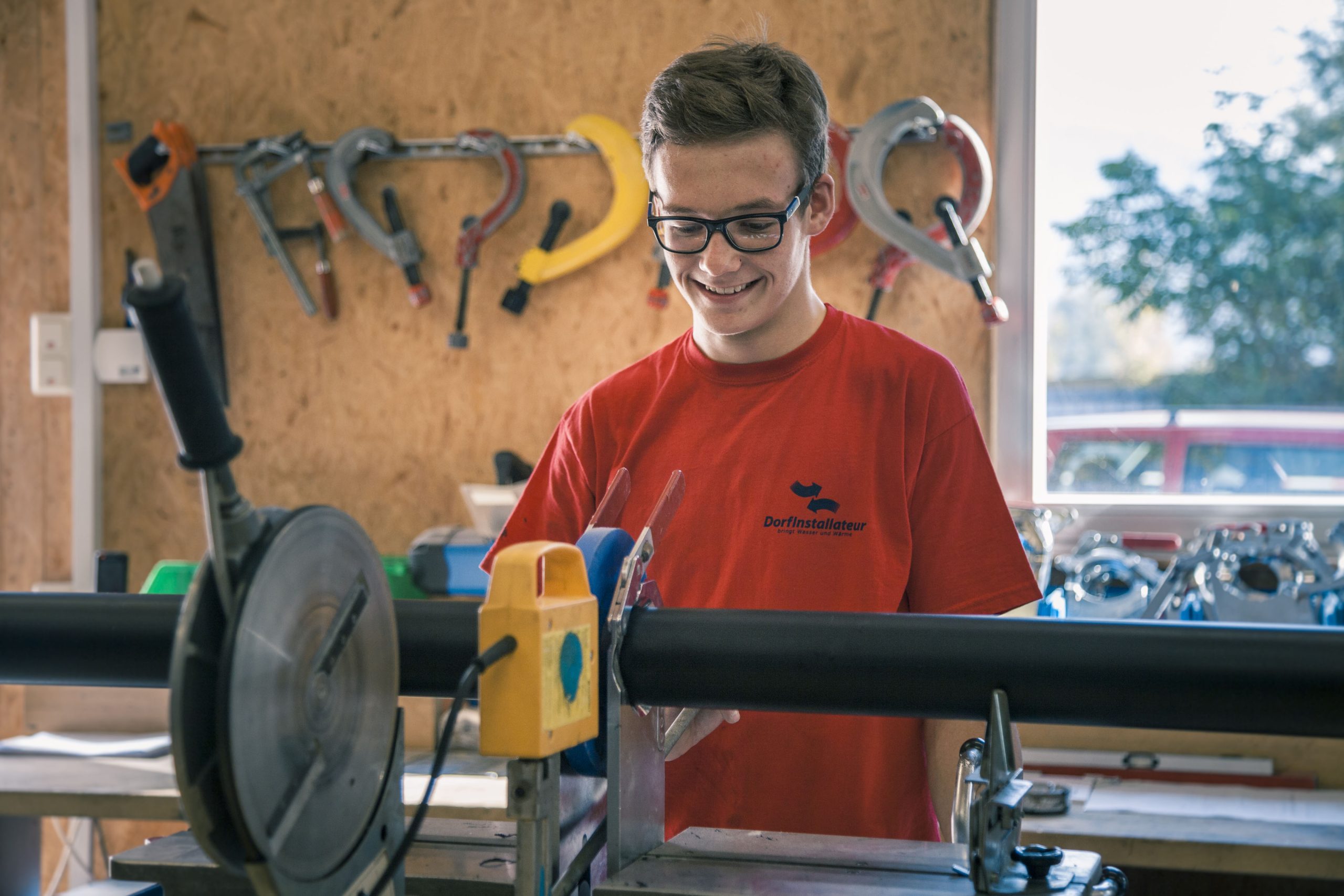 Lehrling bei der Arbeit mit Rohrleitung bei Dorfinstallateur Wolfurt